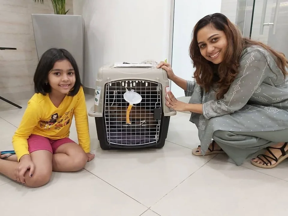 A woman and child sitting beside their pet’s travel carrier