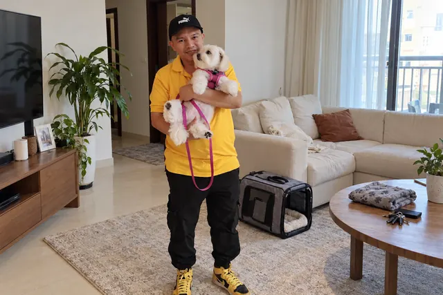 Illustrative scene: Staff member holding a small white dog in a home; not the reviewer’s pet